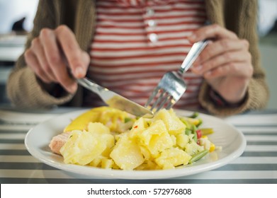 Young Woman Eating Fish And Potatoes