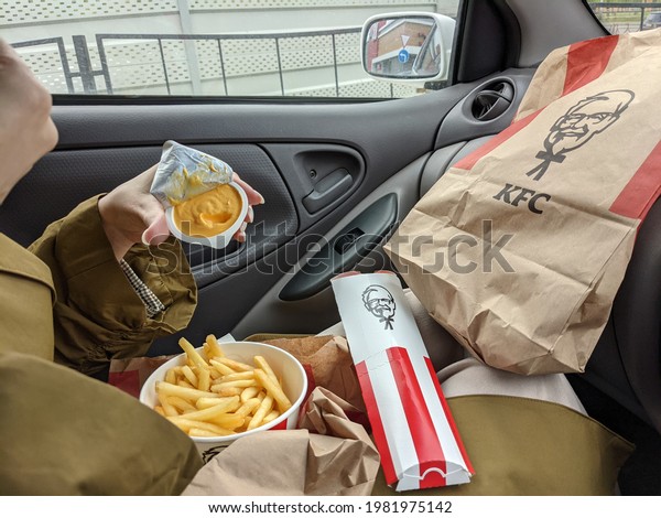 A young woman\
eating food from a fast food restaurant KFC in drive in a car:\
Krasnoyarsk, Russia,\
05.22.2021