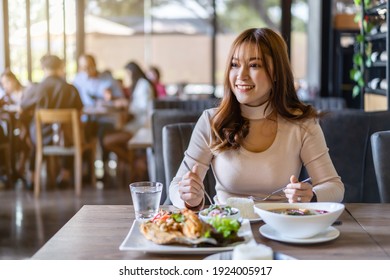 Young Woman Eating With Food In Restaurant