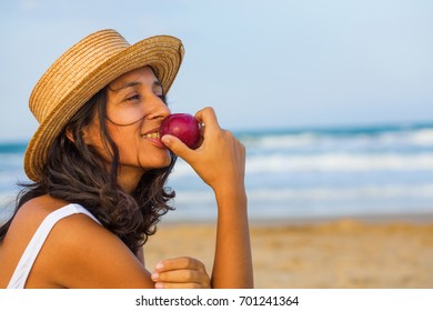 Young Woman Eating Fruit On The Beach