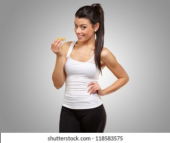 A Young Woman Eating A Granola Bar On Gray Background