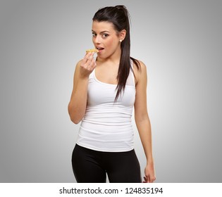 A Young Woman Eating A Granola Bar On Gray Background