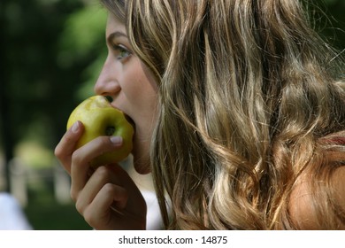 young woman eating a green apple