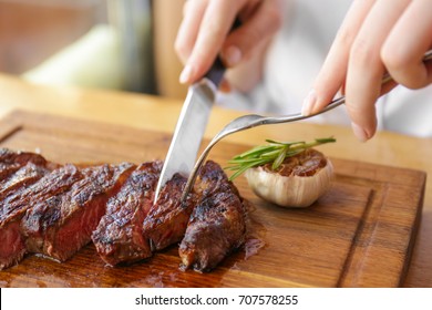 Young Woman Eating Grilled Steak In Restaurant