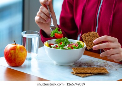 Young Woman Is Eating A Healthy, Fresh, Vegetable Salad With Crisp Rye Bread. Diet And Healthy Lifestyle Concept. Diet And Fiber Food. Proper Nutrition And Eat Right 