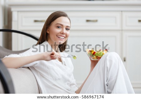 Young woman eating healthy fruit breakfast in bowl at home. Healthy food. Clean eating, dieting, detox, vegetarian food concept.