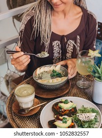 Young Woman Eating Healthy Green Smoothie Bowl