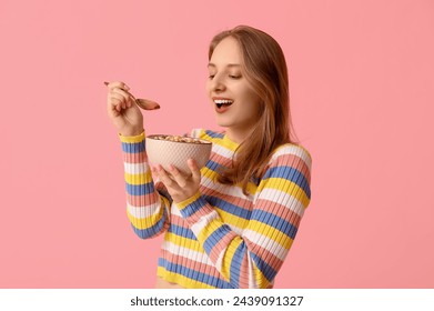 Young woman eating healthy oatmeal on pink background - Powered by Shutterstock