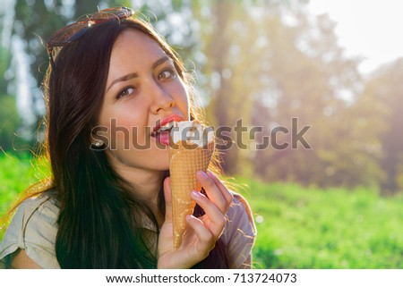 Young woman eating ice cream in the park, woman eating a popsicle in nature 
