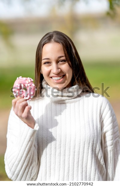 Young woman\
eating an industrial bun\
outdoors