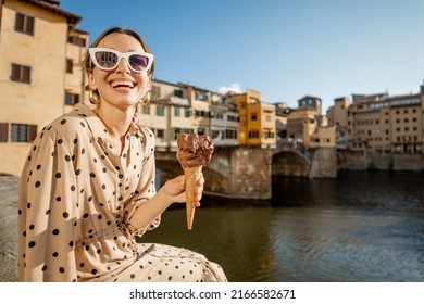 Young woman eating italian ice cream while sitting on the riverside with beautiful view on famous Old bridge in Florence at sunset. Concept of italian gastronomy and landmarks - Powered by Shutterstock