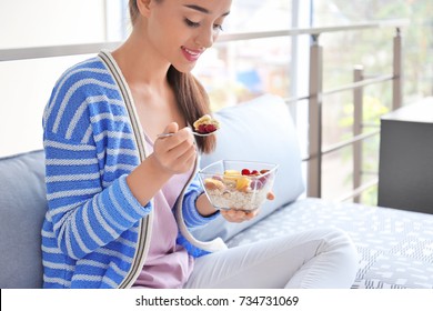 Young Woman Eating Oatmeal In Living Room