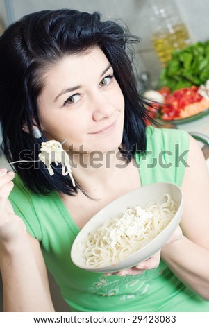 Young woman eating pasta in the kitchen