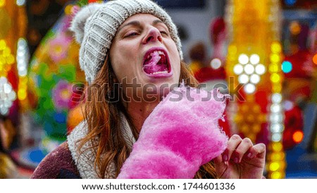 Young woman eating pink cotton candy at a fair