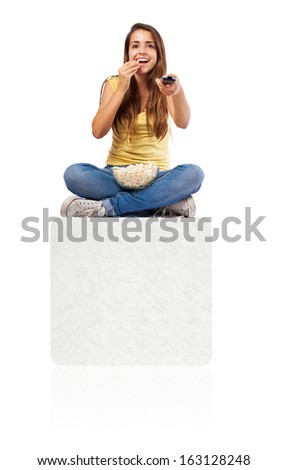 young woman eating popcorn and watching the tv on a white box isolated