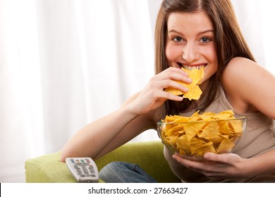 Young Woman Eating Potato Chips In Front Of TV