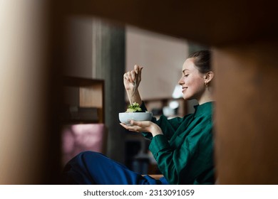 Young woman eating salad in an office. - Powered by Shutterstock