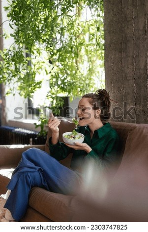 Young woman eating salad in an office.