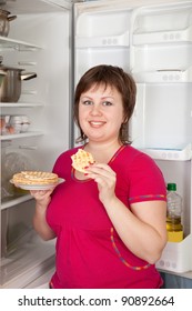 Young Woman Eating  Scone From  Fridge  At Home