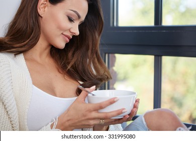 Young Woman Eating Soup By The Window.