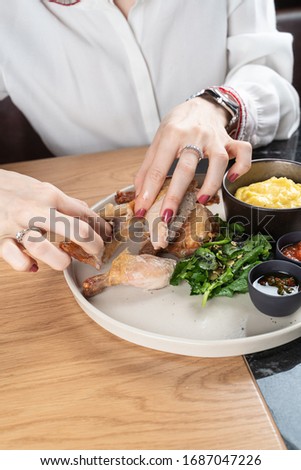 Young woman is eating tabaka chicken with hands in a restaurant