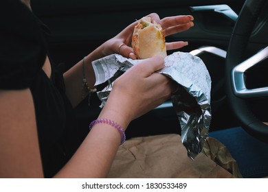 Young Woman Is Eating Take Out Burrito In Her Car