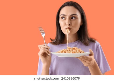 Young woman eating tasty pasta on orange background, closeup - Powered by Shutterstock