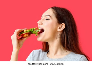 Young woman eating tasty sandwich on color background