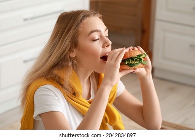 Young Woman Eating Tasty Vegan Burger In Kitchen