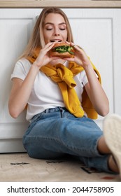 Young Woman Eating Tasty Vegan Burger In Kitchen