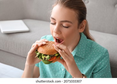 Young Woman Eating Tasty Vegan Burger At Home