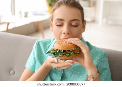 Young Woman Eating Tasty Vegan Burger At Home