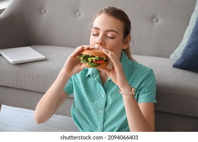 Young Woman Eating Tasty Vegan Burger At Home