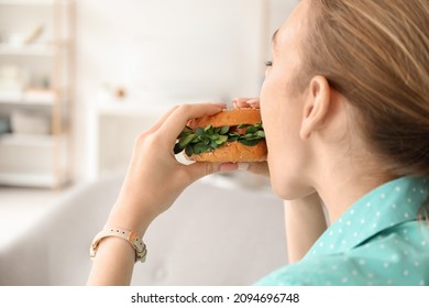 Young Woman Eating Tasty Vegan Burger At Home, Closeup