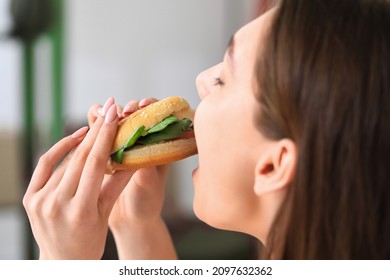 Young Woman Eating Tasty Vegan Burger At Home