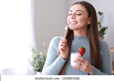 Young Woman Eating Tasty Yogurt At Home