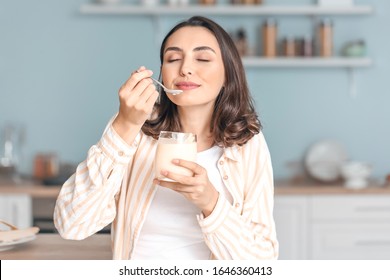 Young Woman Eating Tasty Yogurt At Home