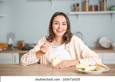 Young Woman Eating Tasty Yogurt At Home