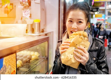 Young Woman Eating Waffle Street Food In Hong Kong