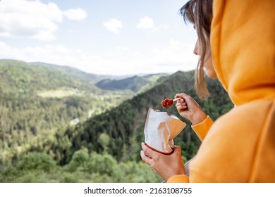 Young woman eats freeze-dried food for hiking from special packaging and enjoys great landscape while traveling high in the mountains. Concept of food and travel in nature - Powered by Shutterstock