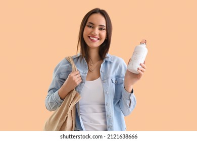 Young woman with eco bag and bottle on beige background - Powered by Shutterstock