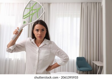 Young Woman With Electric Fly Swatter Indoors. Insect Killer