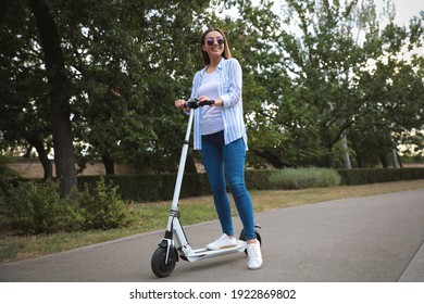 Young Woman With Electric Kick Scooter In Park