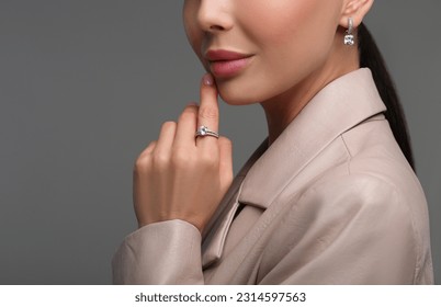 Young woman with elegant jewelry on dark grey background, closeup - Powered by Shutterstock