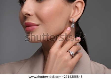 Young woman with elegant jewelry on dark grey background, closeup