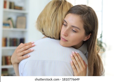 Young woman is embracing her middle aged mother in living room.