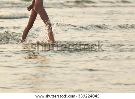 A young woman emerges from the sea after bathing in it at sunset in the summer.