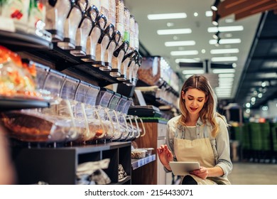 Young woman, employee with apron holding digital tablet and checking condition of product in the store - Powered by Shutterstock