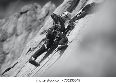 Young Woman Is Engaged In Rock Climbing In The Mountains. Sport Climbing. Black And White.