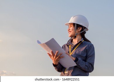 Young Woman Engeneer  Was Standing And Wearing Safety Helmet,  Have Drawing In Your Hand.